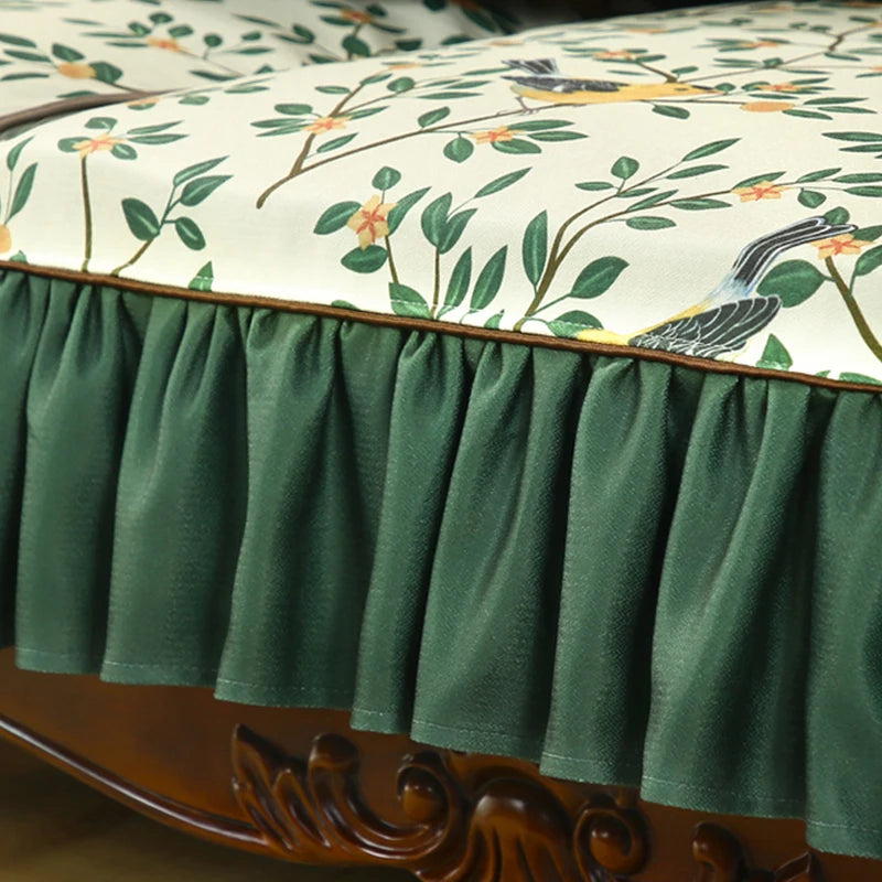Une couverture de lit décorative ornée de motifs végétaux, avec des branches, des fleurs et des oiseaux, dans des tons vert et orange, pour une atmosphère naturelle et chaleureuse.