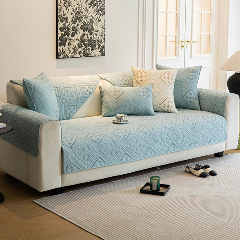 Un canapé élégant et confortable, décoré de coussins en tons de bleu pastel, s'harmonise parfaitement avec le style épuré de la pièce.