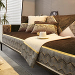 Un canapé aux motifs géométriques dans des tons de marron et d'or, avec de nombreux coussins décoratifs, créant une atmosphère chaleureuse et moderne dans cette pièce.