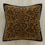 Coussin décoratif avec motif floral doré et noir sur fond blanc cassé.