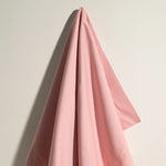 Couverture rose douce et confortable sur fond blanc créant une ambiance apaisante.