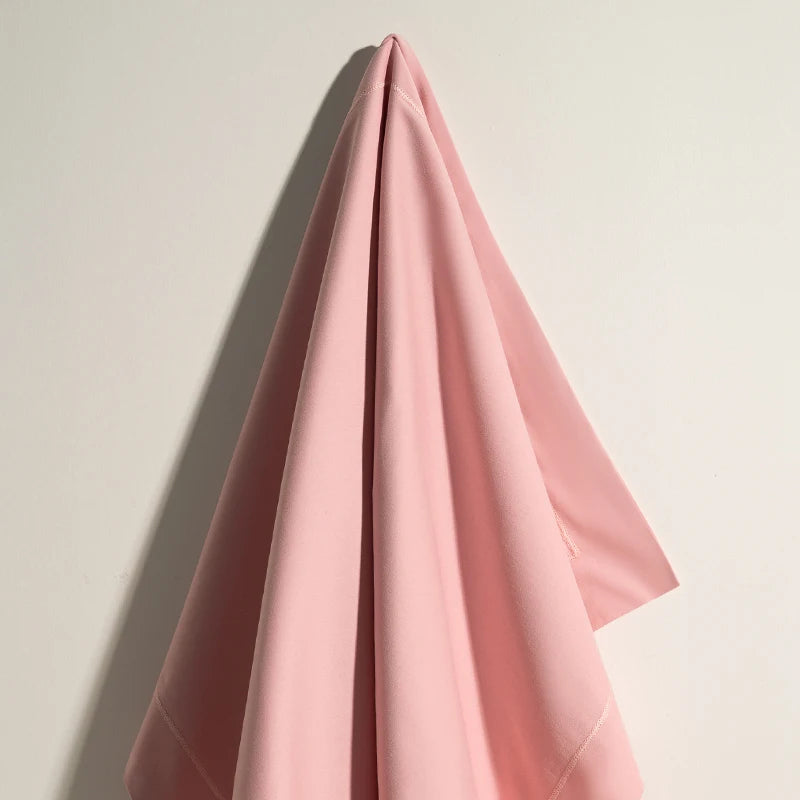 Couverture rose douce et confortable sur fond blanc créant une ambiance apaisante.