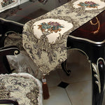 Cette élégante table de salle à manger est recouverte d'un beau chemin de table décoré de motifs floraux et de délicates arabesques, conférant à l'ensemble une atmosphère chaleureuse et raffinée.