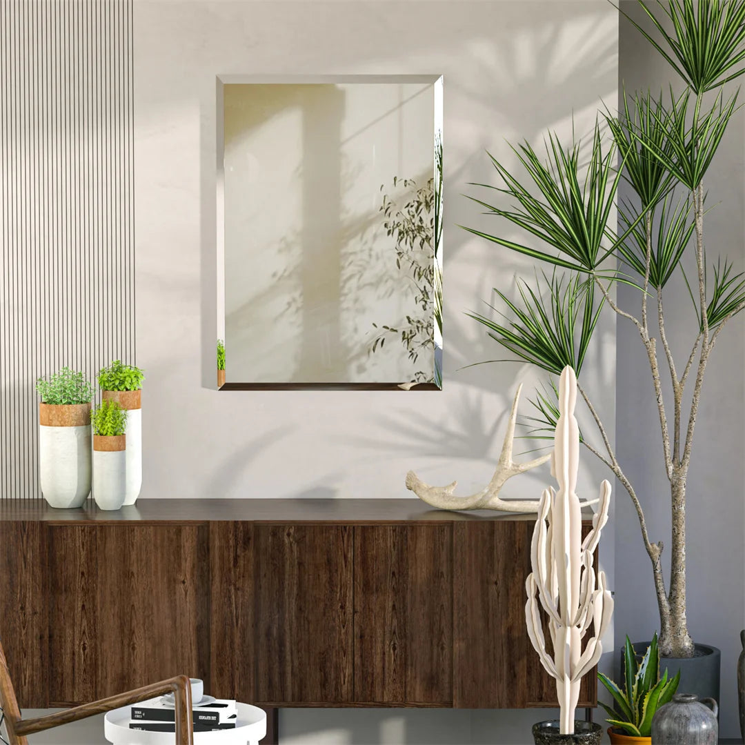 Cette image décorative montre un cadre mural blanc encadré sur un meuble en bois sombre, orné de plantes vertes, de sculptures et d'accessoires décoratifs qui créent une ambiance zen et naturelle.