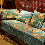 Un canapé rembourré de velours vert avec des motifs floraux dorés, posé sur un meuble en bois sombre, créant une ambiance chaleureuse et élégante dans une pièce aux accents traditionnels.