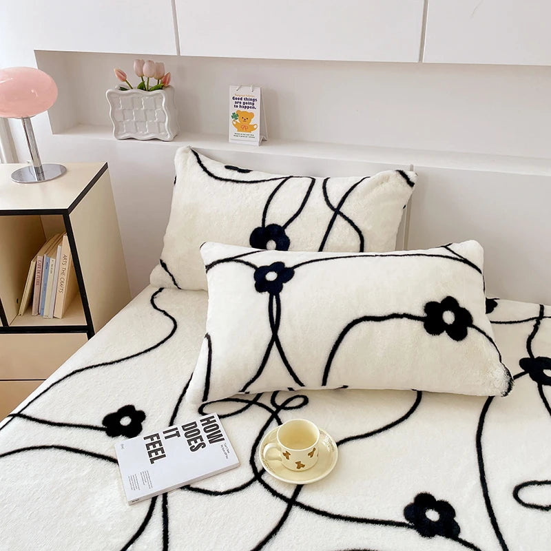 Un confortable ensemble de coussin et couverture avec des motifs floraux stylisés noir et blanc, créant une ambiance sereine et élégante dans un intérieur moderne.