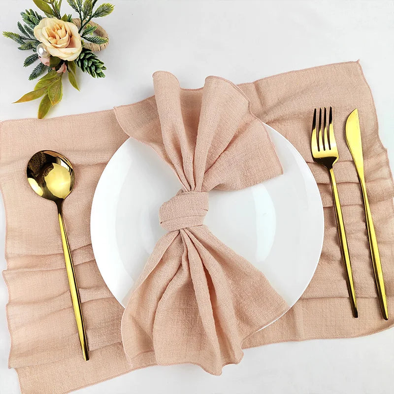 Une table joliment dressée avec des couverts dorés, une serviette beige nouée et une décoration florale, créant une ambiance élégante et invitante.