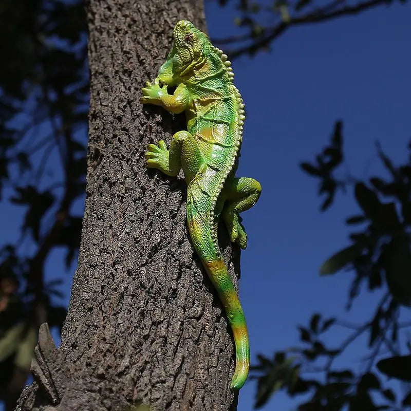 Lézard en résine vert armée posé sur des pierres