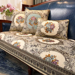 Un canapé en bois avec des coussins décorés de motifs floraux et de bordures ornementées, dans des tons de beige et de bleu, créant une atmosphère élégante et raffinée.