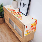 Une belle commode en bois avec une décoration murale colorée, représentant des feuilles d'automne dans des tons chauds, créant une ambiance chaleureuse et harmonieuse dans la pièce.