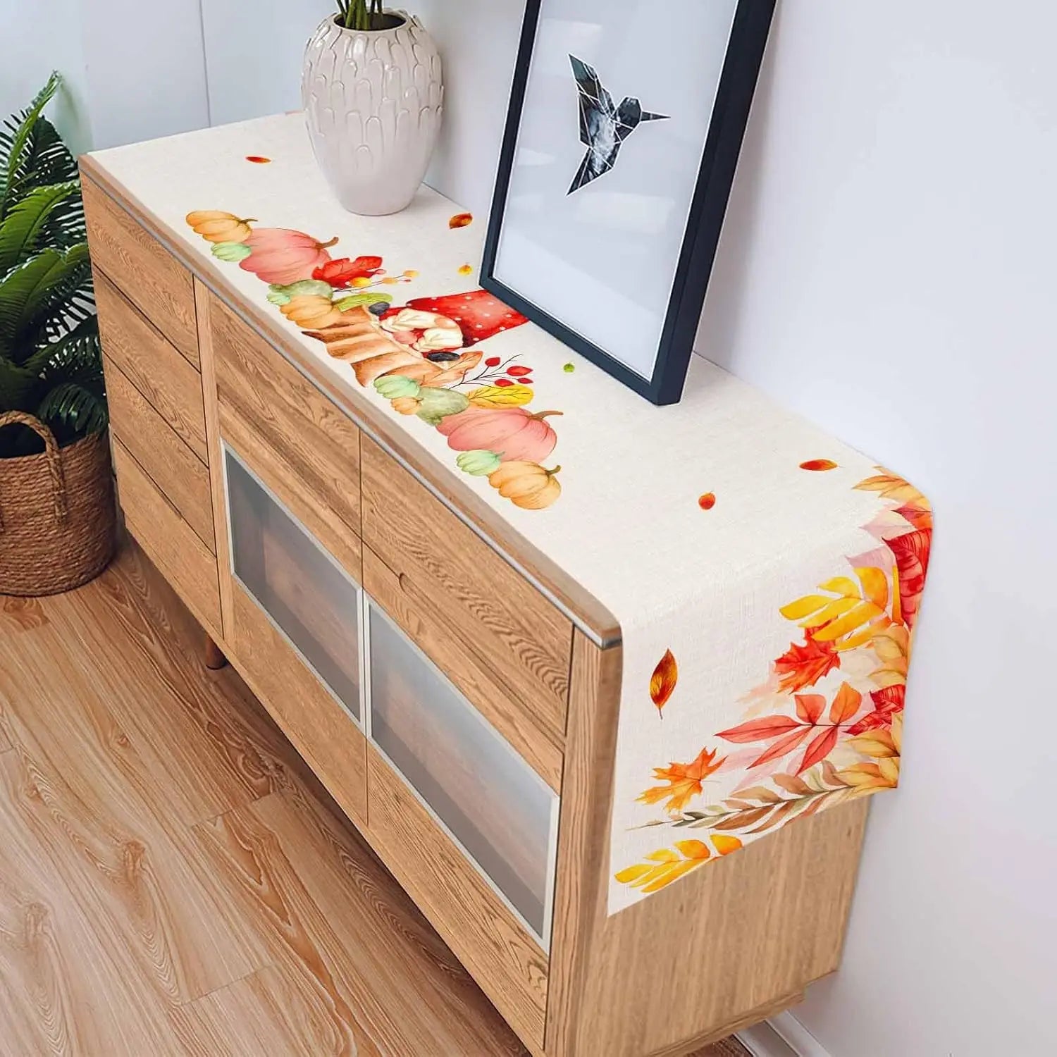 Une belle commode en bois avec une décoration murale colorée, représentant des feuilles d'automne dans des tons chauds, créant une ambiance chaleureuse et harmonieuse dans la pièce.