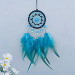 Magnifique attrape-rêves suspendu avec des plumes bleues et vertes, décoré de perles et de cristaux.