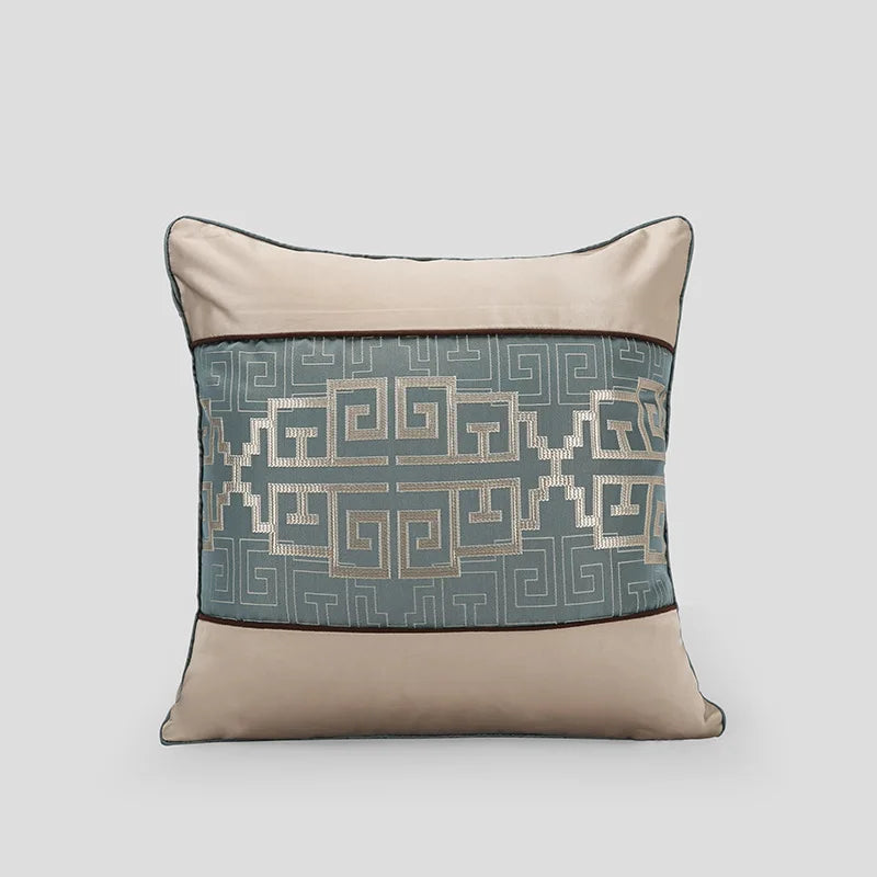 Coussin décoratif beige et gris avec un motif géométrique abstrait.