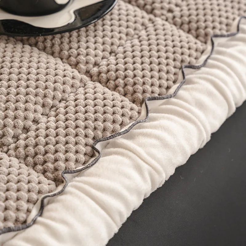 Gros plan sur un pull en maille beige côtelé, avec un bord blanc texturé, posé sur un fond sombre.