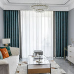 Salon moderne avec rideaux élégants, combinant des draperies bleu marine et voilages blancs. Le salon est aménagé avec un canapé confortable, une table basse en verre, et des éléments décoratifs raffinés. Une ambiance lumineuse et sophistiquée est accentuée par un lustre décoratif suspendu. Parfait pour une décoration intérieure élégante et contemporaine.