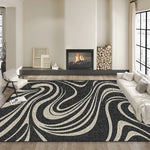 Un tapis moderne et stylisé avec un motif abstrait en noir et blanc, posé sur un sol clair dans un bel intérieur avec une cheminée en arrière-plan.