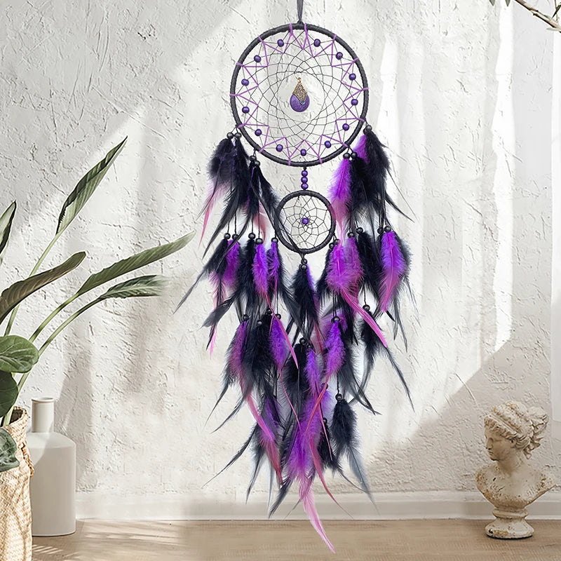 Un attrapeur de rêves décoratif aux plumes violettes et noires, suspendu au mur sur un fond clair.