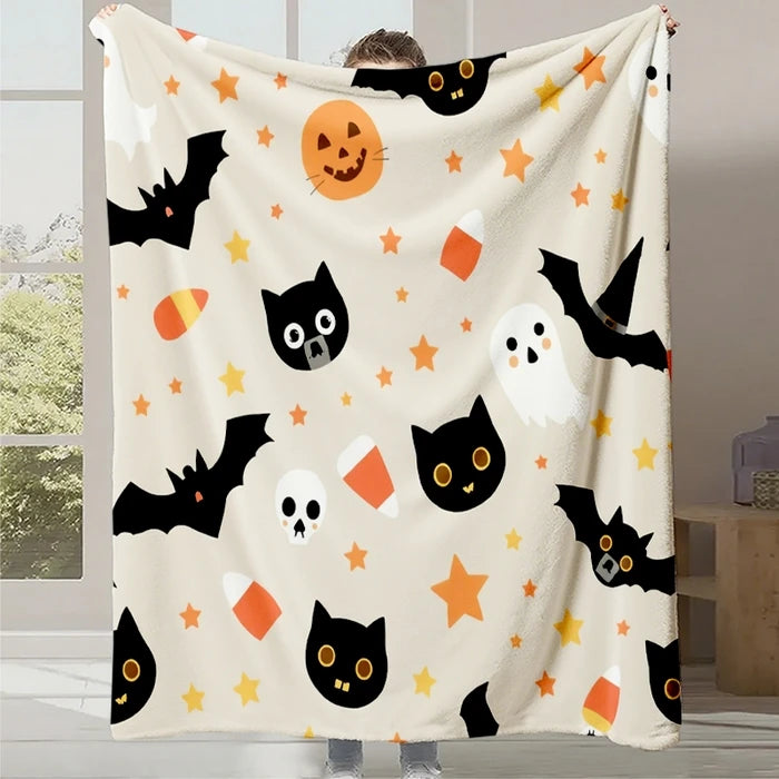 Une couverture douce et moelleuse ornée de chats noirs, de chauves-souris et de citrouilles d'Halloween, évoquant une atmosphère festive et cosy.