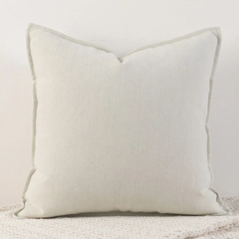 Coussin décoratif blanc avec des bords lisses et un motif de texture sur la surface.