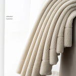 Couverture douillette beige posée sur un fauteuil élégant, ajoutant une touche de confort et de style à votre décoration intérieure. Idéale pour créer une atmosphère chaleureuse dans votre salon ou chambre.