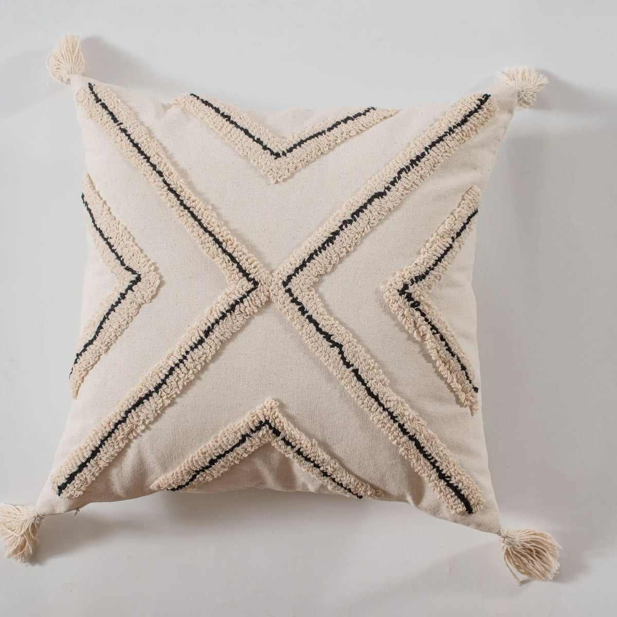 Coussin beige avec motifs noirs géométriques et franges.