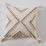 Coussin beige avec motifs noirs géométriques et franges.