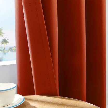 Gros plan sur un rideau drapé orange brûlé avec texture en tissu épais, partiellement ouvert, laissant entrevoir un paysage tropical à l'extérieur.
