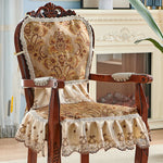 Un magnifique fauteuil vintage en bois foncé, avec un dossier sculpté et un rembourrage décoré de motifs floraux dorés et de dentelle élégante, offrant un charme raffiné et une touche de luxe à l'ameublement.