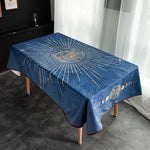 Une nappe décorative de table bleu foncé ornée de motifs dorés représentant le soleil et les phases de la lune.