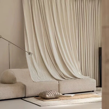 Canapé moderne beige avec coussin décoratif et rideaux élégants dans un salon minimaliste. Espace harmonieux offrant confort et sophistication, idéal pour rehausser le style intérieur.