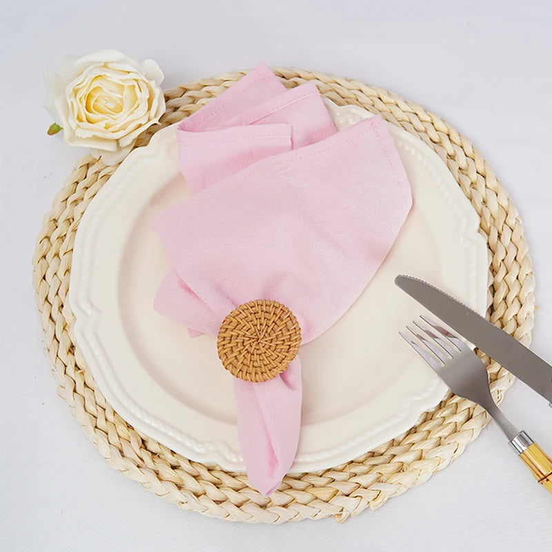 Une belle assiette avec une serviette rose, une rose blanche et des couverts sur un set de table en fibres naturelles.