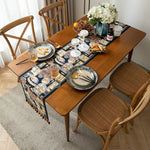 Une table en bois avec une nappe rayée, remplie de plats et de verres, ainsi que des fleurs, créant une scène conviviale et chaleureuse.