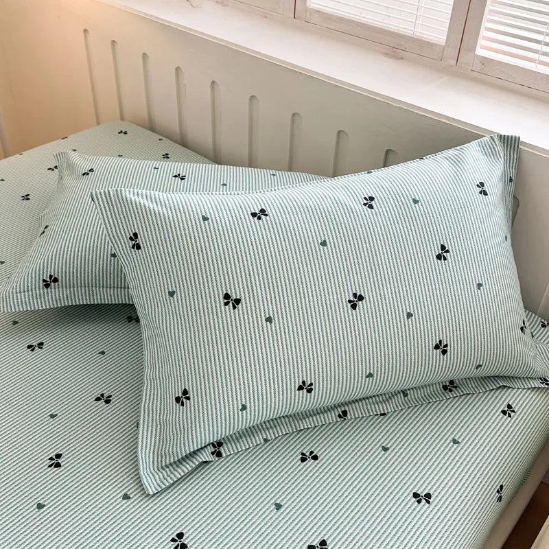 Parure de lit en coton rayé verts et noirs à motifs de nœuds papillon, créant une ambiance chaleureuse et apaisante dans la chambre.