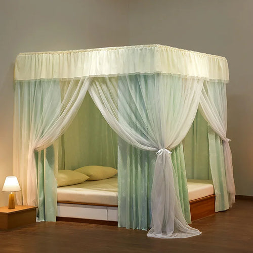 Lit à baldaquin en bois naturel avec rideaux blanc et vert clair suspendu au plafond, donnant une touche élégante et aérée à la chambre.