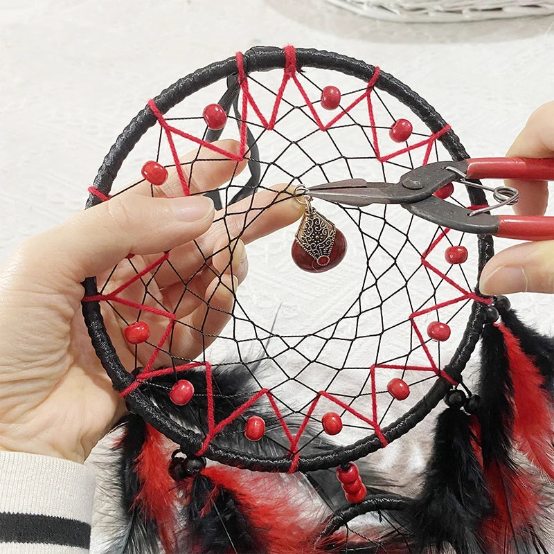 Capteur de rêves artisanal avec un motif en réseau décoré de perles rouges et de plumes noires.