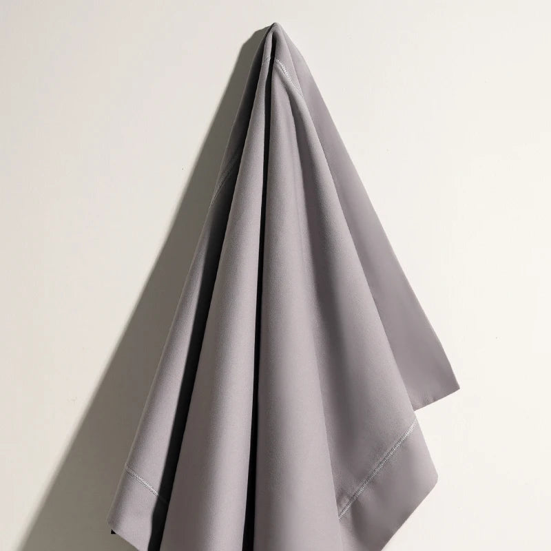 Un simple et élégant rideau gris clair suspendu sur un mur clair.