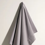 Un simple et élégant rideau gris clair suspendu sur un mur clair.