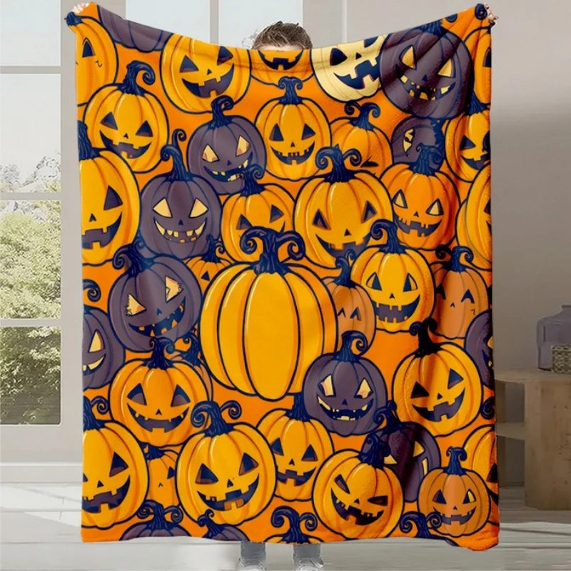 Une couverture orange ornée de citrouilles sculptées d'Halloween, aux expressions malicieuses et aux formes variées, créant une atmosphère festive pour la saison.
