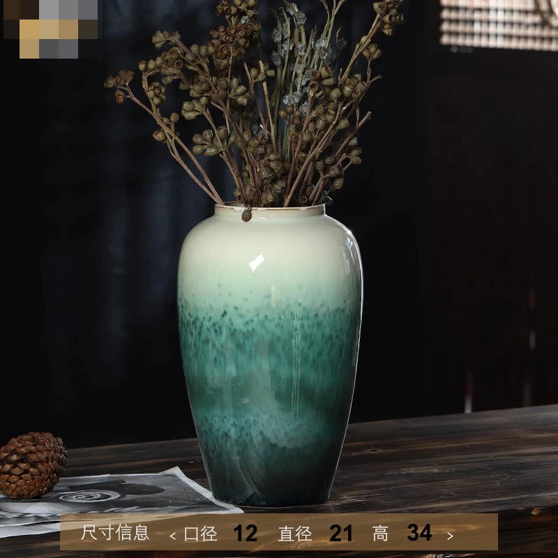 Un vase en céramique de couleur vert dégradé rempli de fleurs séchées.