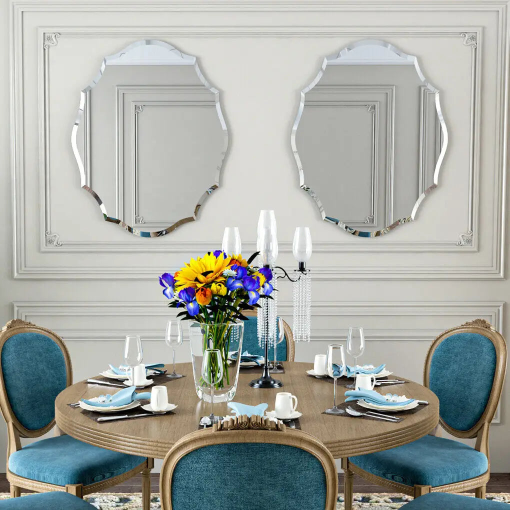 Élégante salle à manger avec table ronde en bois, chaises bleu canard, miroirs décoratifs encadrés et bouquet de fleurs colorées dans un vase sur la table.