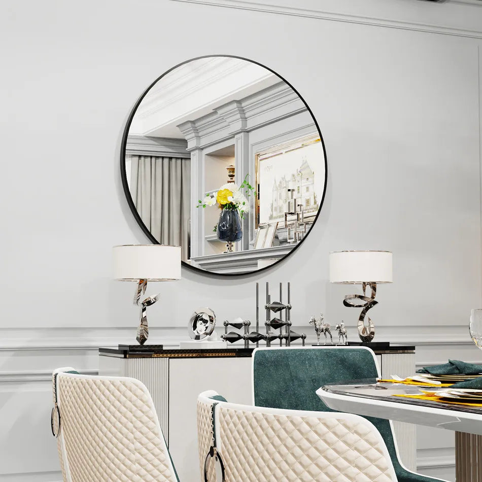 Reflet élégant dans un miroir rond encadré, avec un arrangement floral et des objets de décoration sur un buffet en bois sombre, dans une pièce élégante aux murs gris et blancs.