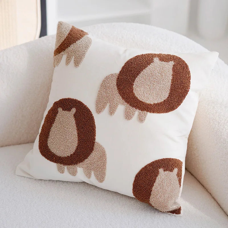 Coussin décoratif avec des motifs d'animaux mignons en formes abstraites sur un fond blanc.