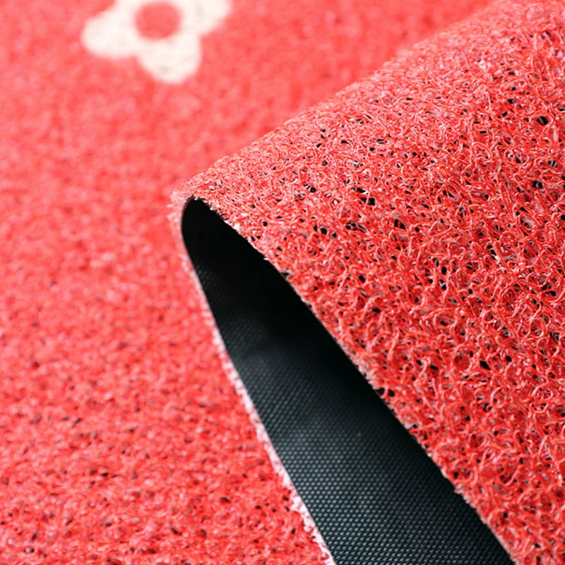 Un gros plan sur un tapis de sol rouge avec une texture granuleuse et rugueuse, souligné par une bande noire.