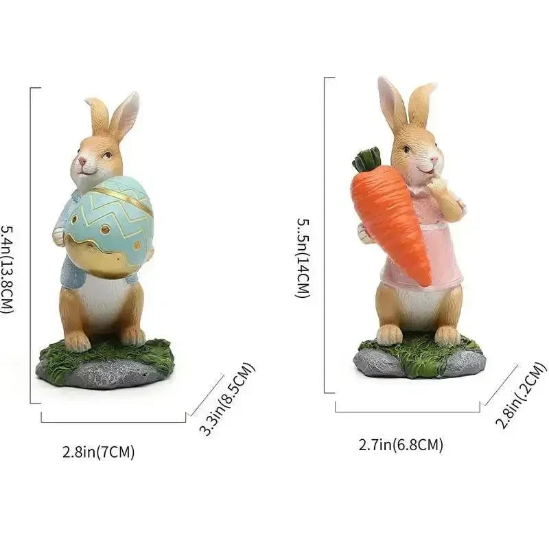 Deux lapins de Pâques en résine, l'un tenant un œuf décoré et l'autre une carotte, posés sur une herbe verte, représentant les symboles traditionnels de cette fête.