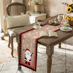 Une table en bois décoré de motifs de Noël, avec des coussins, des fleurs, des fruits et des pâtisseries, créant une scène cosy et festive.