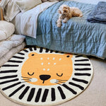 Un tapis rond représentant une figure de tigre avec un motif en rayures noires et blanches, sur un lit recouvert d'une couette en nuances de bleu.