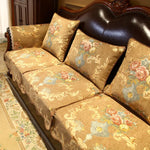 Un canapé vintage richement orné de motifs floraux dorés, avec des coussins assortis, placé dans un cadre élégant et orné.