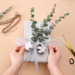 bouquet artificiel feuilles vertes naturel minimaliste ruban blanc vase blanc tapis beige ornement extérieur