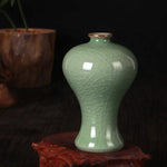 Magnifique vase de porcelaine céladon de style chinois, avec un motif textural élégant, posé sur un support en bois sombre.