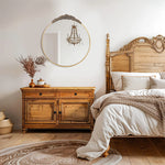 La chambre à coucher élégante présente un mobilier en bois sculpté et un miroir rond vintage, créant une ambiance chaleureuse et raffinée.